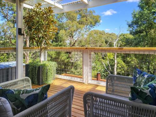 a screened porch with two chairs on a wooden deck at Locarno Cottage in Hepburn Springs