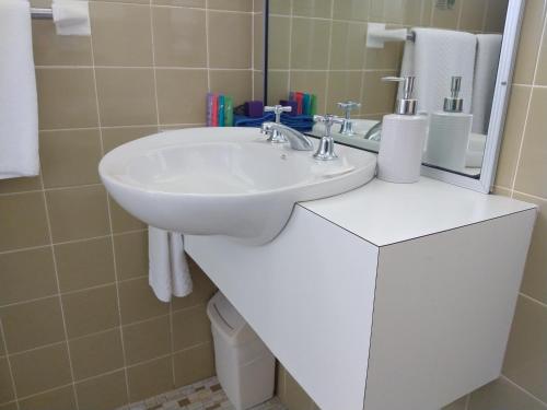 y baño con lavabo blanco y espejo. en Haven Waters Motel & Apartments, en North Haven