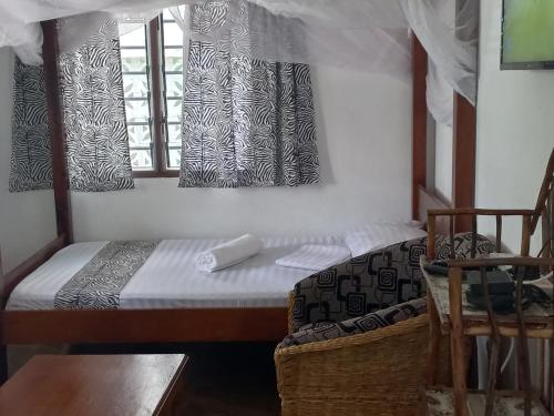 um pequeno quarto com uma cama e uma janela em New Muna House. em Ukunda