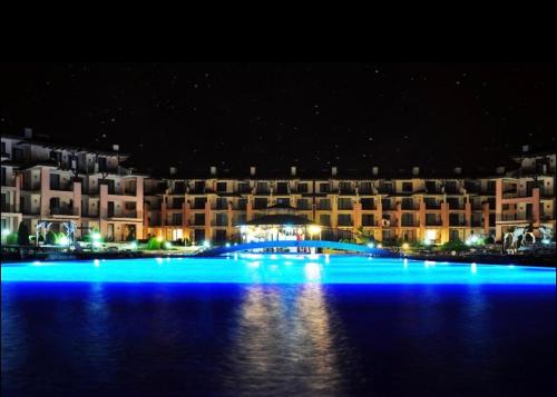 ein großes Gebäude mit blauen Lichtern im Wasser in der Nacht in der Unterkunft Alex-part Kaliakria resort in Kawarna