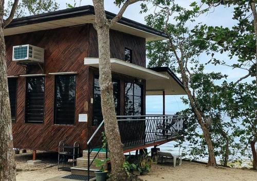 a wooden house with a balcony and a tree at Tabique by the sea in Cebu City