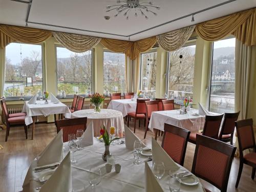 a dining room with tables and chairs and windows at Hotel Haus am See in Simmerath