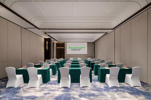 a conference room with tables and chairs and a screen at Wyndham Garden Hangzhou Yuhang in Hangzhou