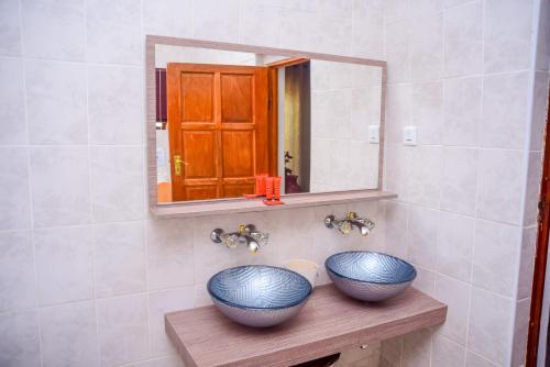 zwei blaue Schüsseln auf einem Holzregal im Badezimmer in der Unterkunft African Home Hotel in Gaborone