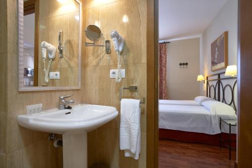 a bathroom with a sink and a bedroom with a bed at Apartamentos Murillo in Seville