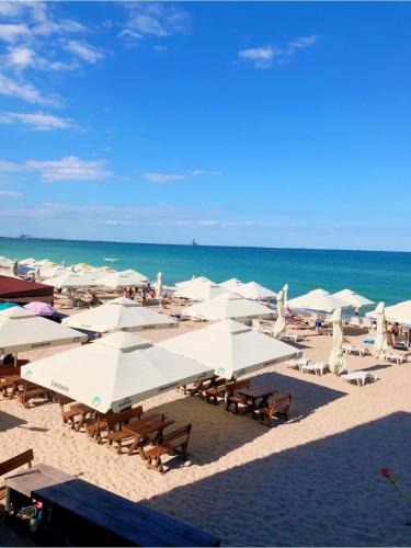 a beach with white umbrellas and chairs and the ocean at Aqua Villa by the Sea in Eforie Sud