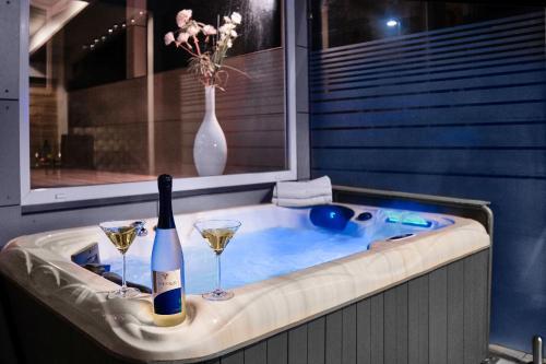 a hot tub with a bottle of wine and two glasses at Ferienhaus am Millibach in Wehingen