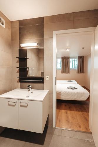 a bathroom with a sink and a bed at Le Loup Gris - 35 pers - Vue-Wellness, Butgenbach-Malmedy in Butgenbach