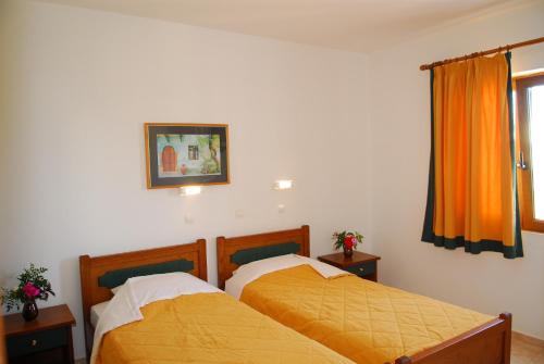 two beds in a bedroom with orange sheets at Apollo City Hotel - Maliatim in Malia