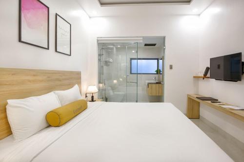 a bedroom with a white bed with a yellow pillow at Continent Apartment in Da Nang