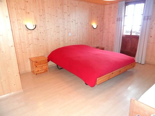 a bedroom with a red bed with a red blanket at Helvetia in Troistorrents