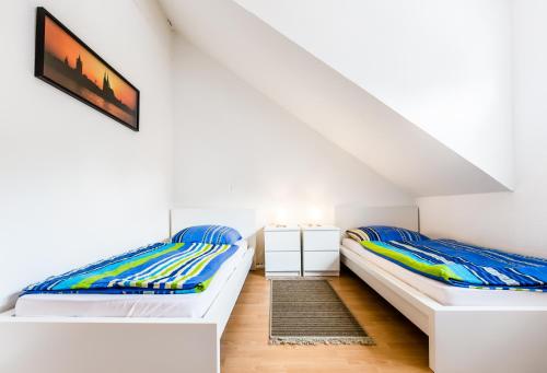 Habitación con 2 camas, paredes blancas y suelo de madera. en Ferienhaus Köln en Colonia