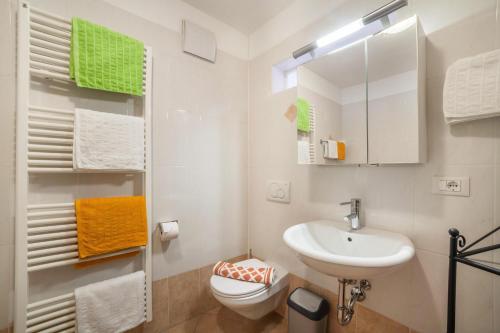 een badkamer met een wastafel, een toilet en een spiegel bij Ferienwohnung Ortler in Saltusio