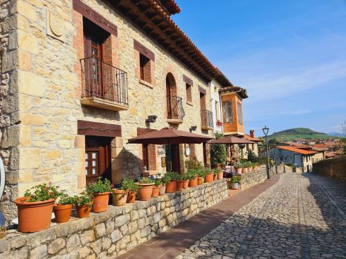 ein Steingebäude mit Topfpflanzen und Sonnenschirmen auf einer Straße in der Unterkunft Hospederia Santillana in Santillana del Mar