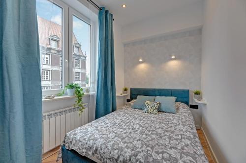 a bedroom with a bed and a large window at Ideal Apartments Arkady in Gdańsk