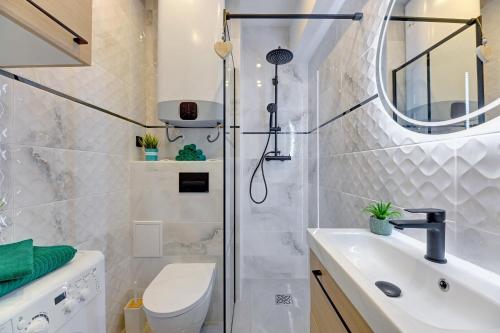 a bathroom with a shower and a toilet and a sink at Ideal Apartments Arkady in Gdańsk