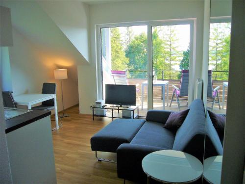 uma sala de estar com um sofá azul e uma varanda em Apartments am Rehgehege Apartment 4 3 OG em Überlingen