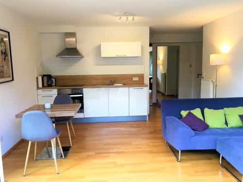 ein Wohnzimmer mit einem blauen Sofa und einer Küche in der Unterkunft Apartments am Rehgehege Apartment 1 EG in Überlingen