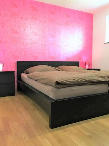 a bedroom with a bed with a pink wall at Apartments am Rehgehege Apartment 1 EG in Überlingen
