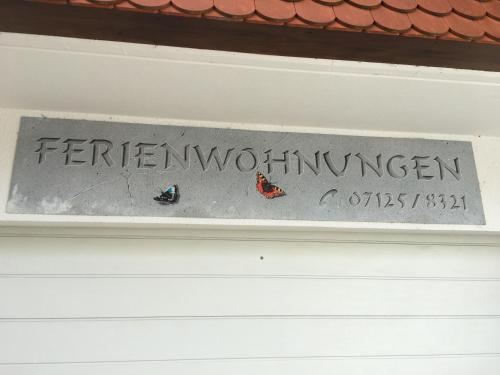 een bord op een witte deur met vlinders erop bij Haus Am Sonnenhügel in Bad Urach