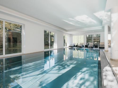 a swimming pool in a house with glass walls at Hotel Vier Jahreszeiten by VAYA in Kaprun