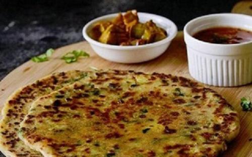 Una tabla de cortar de madera con una pizza y un tazón de comida. en Lamrin Norwood Green Palampur, Himachal Pradesh, en Pālampur