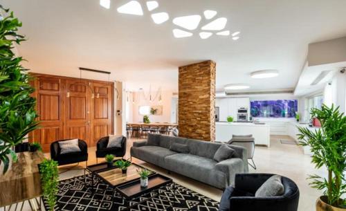 - un salon avec un canapé gris et des chaises dans l'établissement YalaRent Villa Enorma with Private Pool, à Eilat