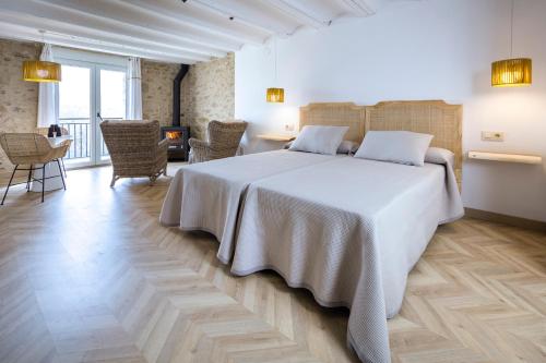 Un dormitorio con una gran cama blanca y sillas en 40 de Mayo en Cantavieja