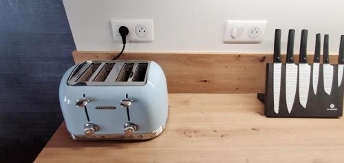 a toaster sitting on a wooden counter next to two knives at L'HIVERNET, grand Triplex neuf au cœur d'Embrun accès facile in Embrun