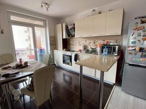 a kitchen with a table and a refrigerator at Sofia Apartments in Floreşti