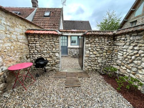 a stone house with a red chair and a brick wall at Maison climatisée avec jardin in Vernon