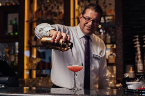 a man in a tie pouring a drink into a glass at Radisson Blu Resort, Malta St. Julian's in St Julian's