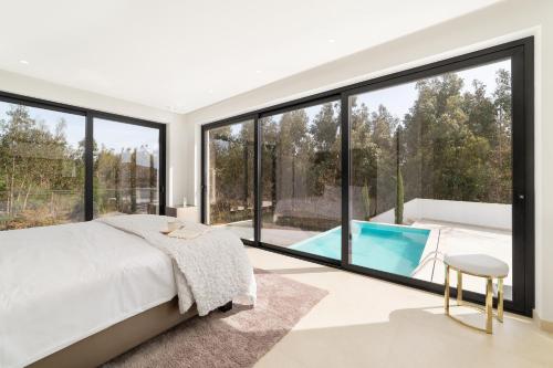 a bedroom with a large window and a pool at Villa Floresta - By SCH in São Martinho do Porto