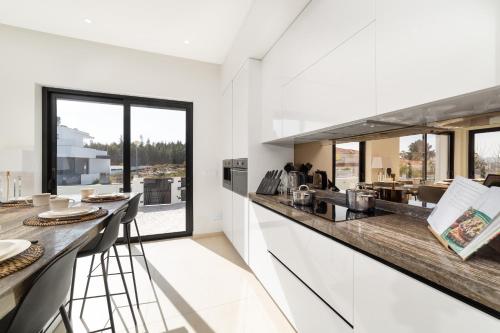 a kitchen with white walls and a counter with stools at Villa Floresta - By SCH in São Martinho do Porto
