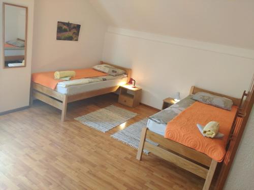 two beds in a small room with wooden floors at Rooms "Nada Zunic" in Knin