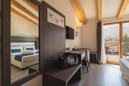 a hotel room with a bed and a desk and a mirror at Hi Hotels Trento - Wellness & Spa Adults Only in Trento