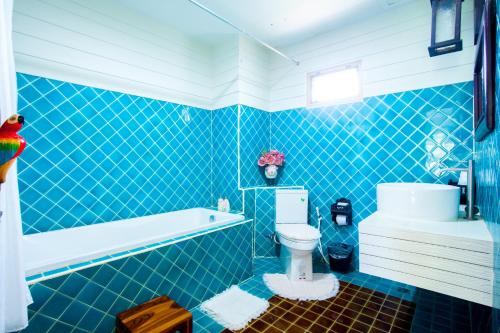 y baño de azulejos azules con aseo y bañera. en P.Paradise Hotel, en Kamphaeng Phet