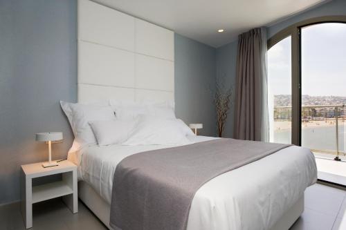 een slaapkamer met een groot bed en een groot raam bij Hotel Boutique La Mar - Adults Only in Peñíscola