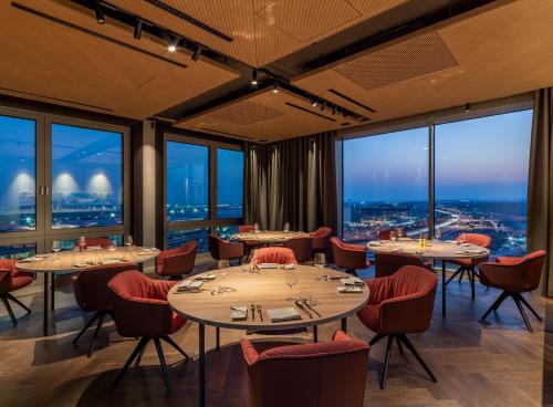 a restaurant with tables and chairs and large windows at b'mine Hotel Frankfurt Airport in Frankfurt/Main