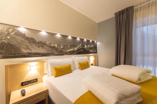 a bedroom with a large white bed with yellow pillows at Hi Hotels Trento - Wellness & Spa Adults Only in Trento