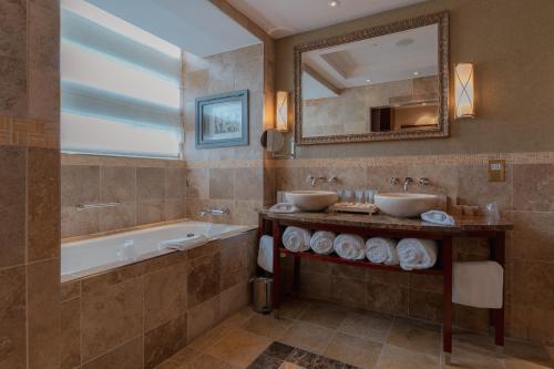 a bathroom with two sinks and a tub and a mirror at Fota Island Hotel and Spa in Cork