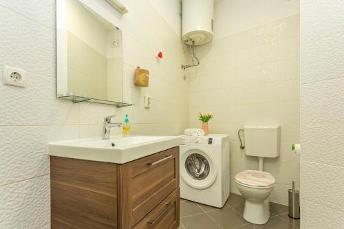 a bathroom with a sink and a washing machine at Old Market Residence in Šibenik