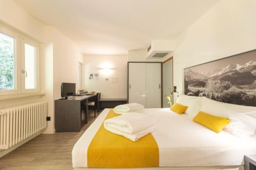 a bedroom with a large white bed with yellow pillows at Hi Hotels Trento - Wellness & Spa Adults Only in Trento