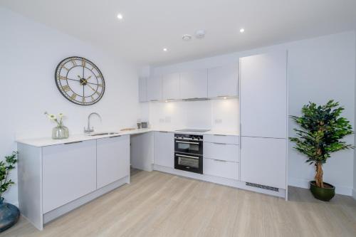 a kitchen with white cabinets and a clock on the wall at 5 Middlecombe - Luxury Apartment at Byron Woolacombe, only 4 minute walk to Woolacombe Beach! in Woolacombe