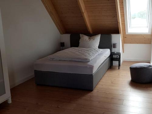 uma cama num quarto com tecto em madeira em Skandinavische Ferienwohnung auf Gut Bennewohld JH em Heide