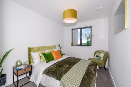 a bedroom with a bed and a chair and a window at 5 Middlecombe - Luxury Apartment at Byron Woolacombe, only 4 minute walk to Woolacombe Beach! in Woolacombe