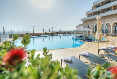 a beach with a pool, chairs, and a pool table at Radisson Blu Resort, Malta St. Julian's in St Julian's
