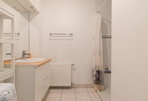 La salle de bains blanche est pourvue d'un lavabo et d'une douche. dans l'établissement LES CELTES - Appartement pour 6, à Saint-Nazaire