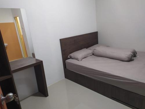 a small bedroom with a bed and a table at Rooms at Josapa Guest House in Batam Center