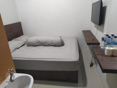 ein kleines Bett in einem Zimmer mit Waschbecken und Waschbecken in der Unterkunft Rooms at Josapa Guest House in Batam Center